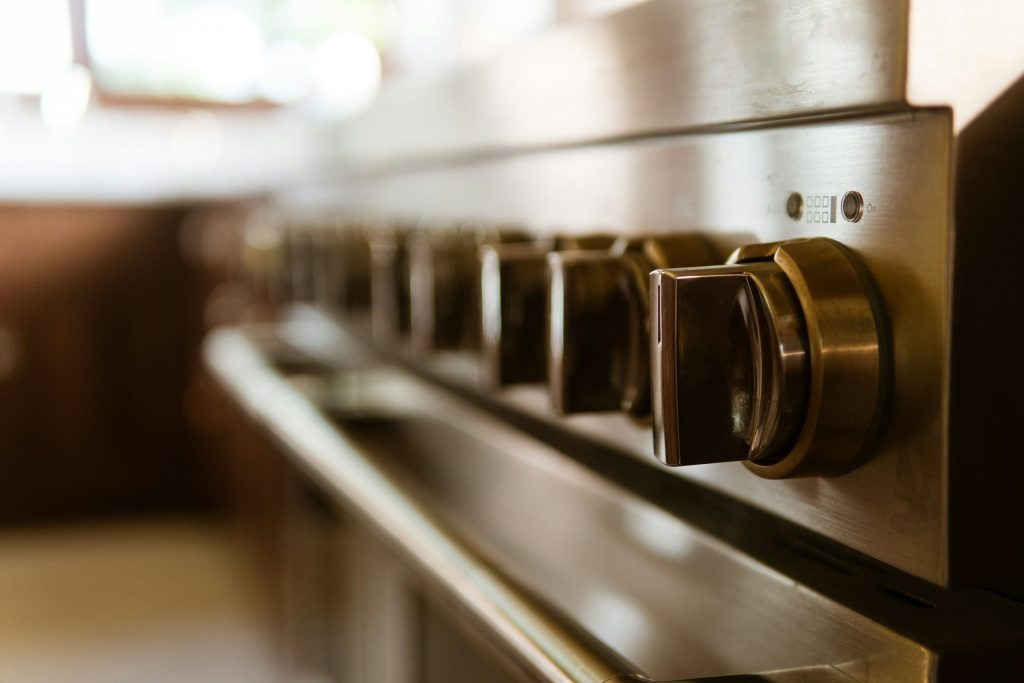 Brass control knobs on a range, the kitchen soft behind them