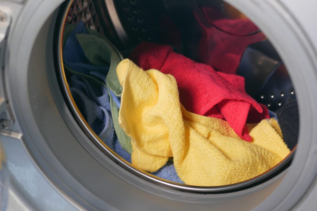 Brightly colored towels inside the drum of a front-loading machine, seen through the open door