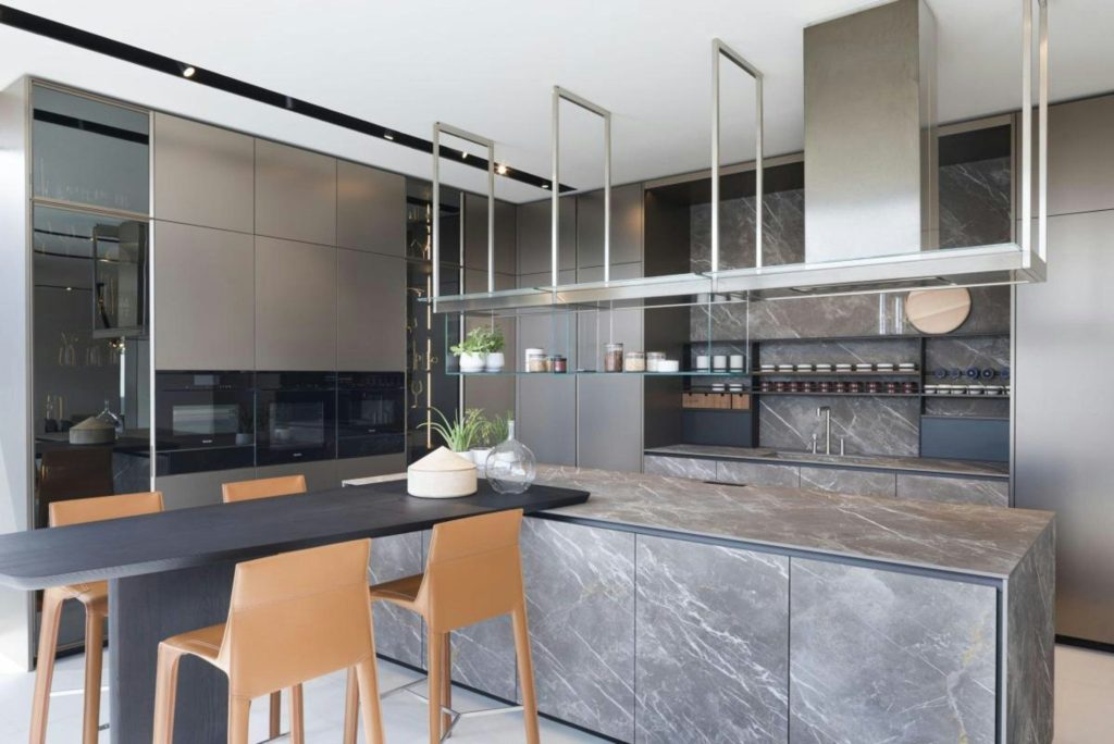 A grey marble kitchen with a long island and a suspended shelf