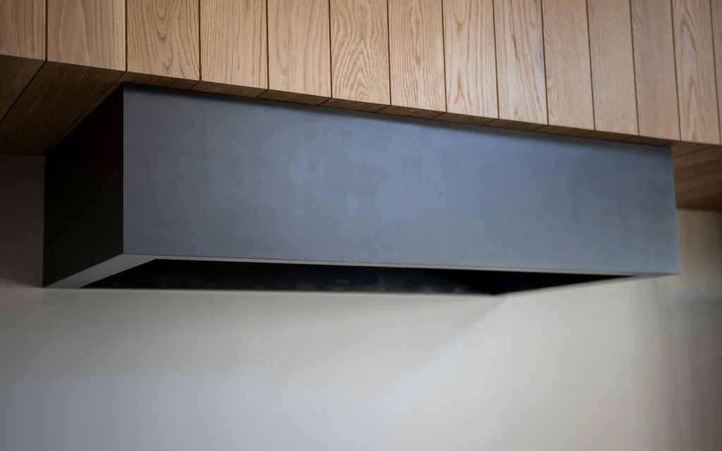 A dark rectangular extractor hood under a timber ceiling