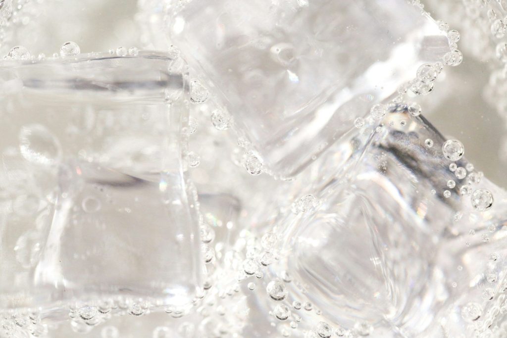 Ice cubes and bubbles in clear water, close up