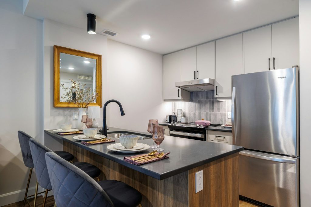 A breakfast island laid for four, a stainless refrigerator behind it