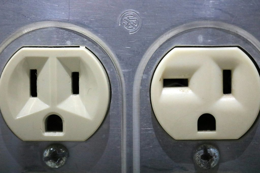Two worn outlets in an old metal wall plate, close up