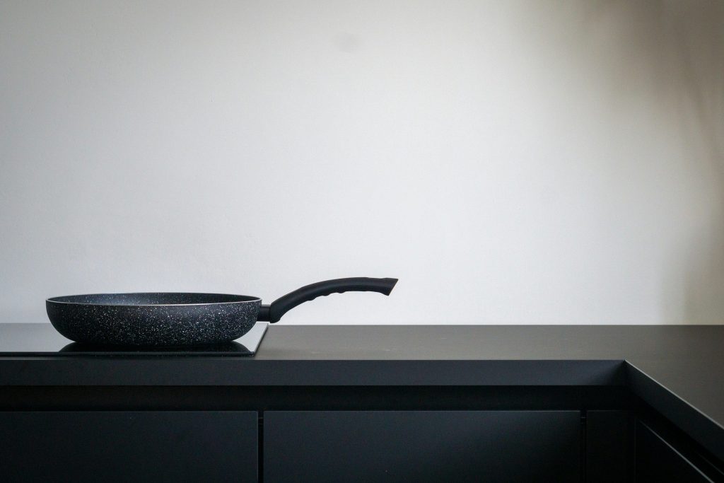 A speckled frying pan on an induction hob set into a dark counter