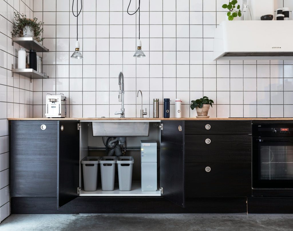 An open under-sink cabinet with waste bins and a filter unit