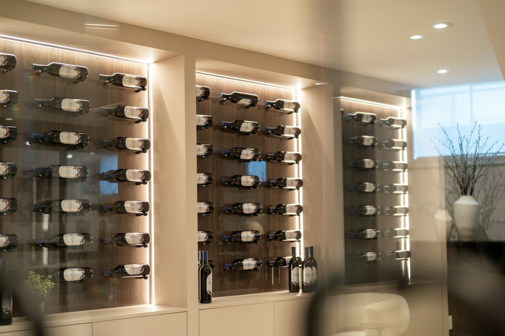 A lit wine wall of horizontal racks in a pale living room