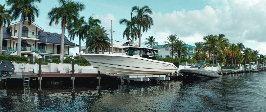 Boats on their lifts behind waterfront houses lined with palms