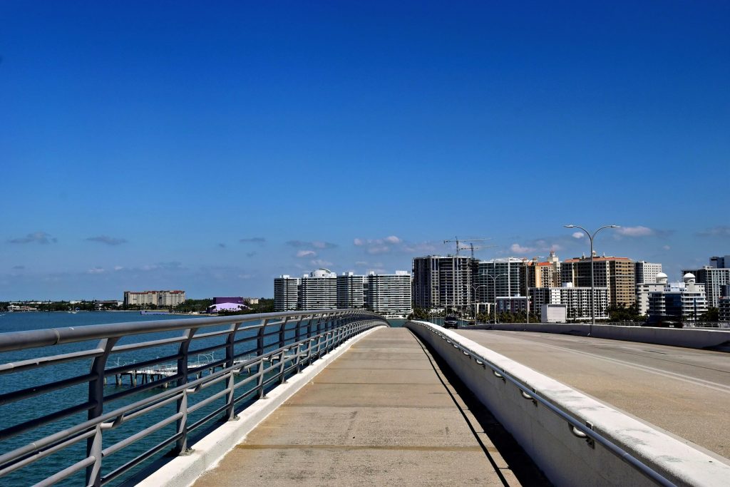 A causeway running toward a waterfront city of towers