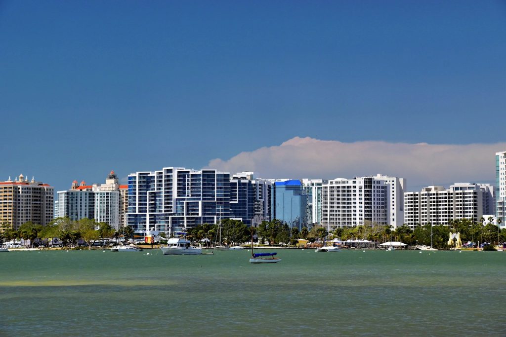 A waterfront of apartment blocks of several eras seen across a mooring field