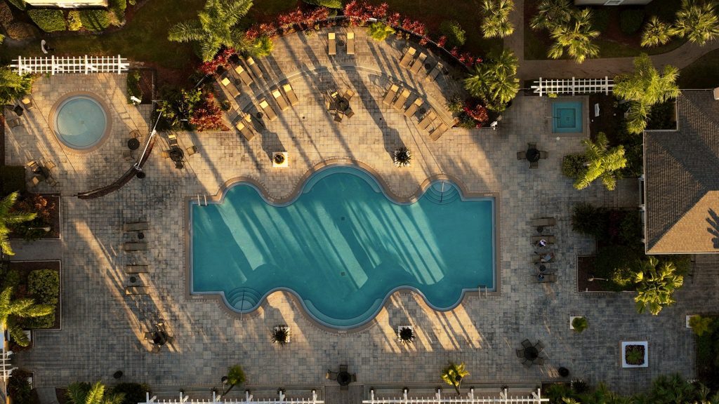 A community pool deck with loungers and a spa, straight down