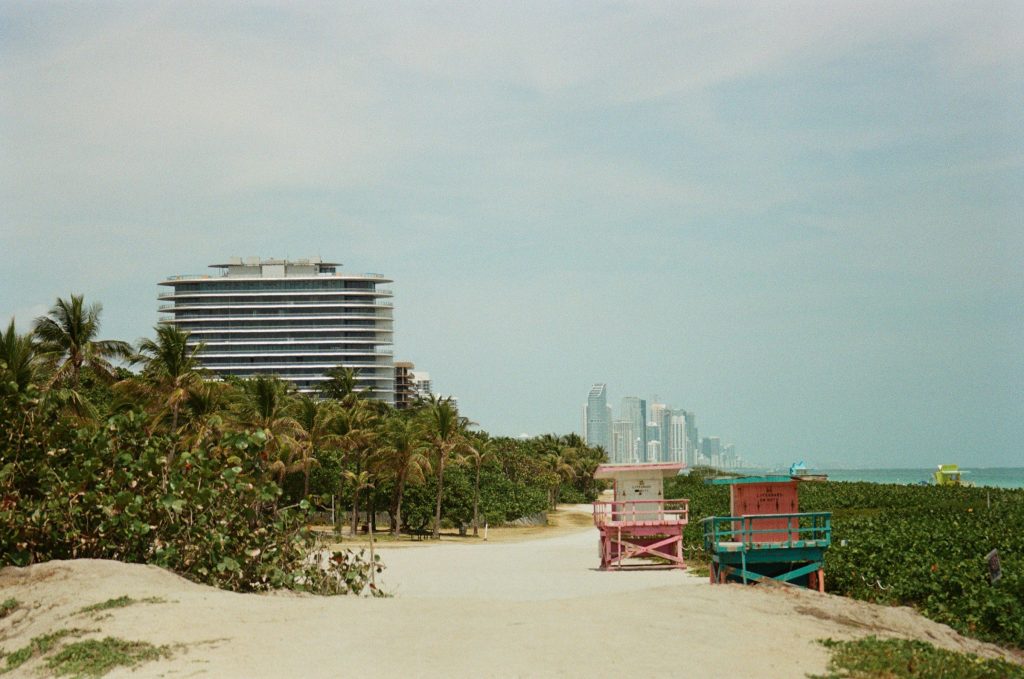 Beach huts on a dune, a long apartment block behind the sea grape