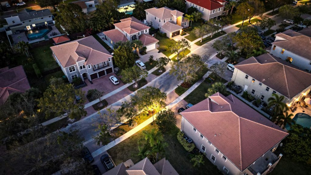 Large tile-roofed houses along a lit street at dusk, from above