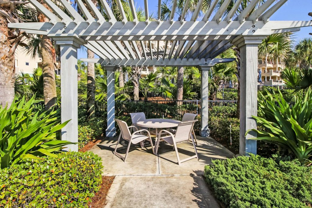 A pergola with a table and chairs in a planted courtyard