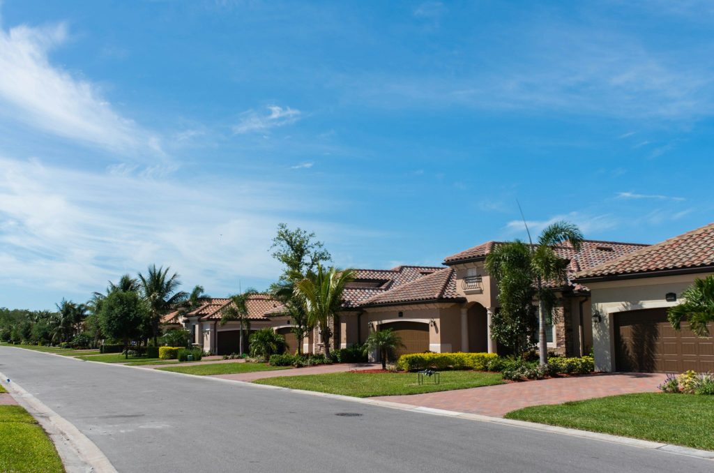 A street of tile-roofed houses built to one specification, palms along the verge