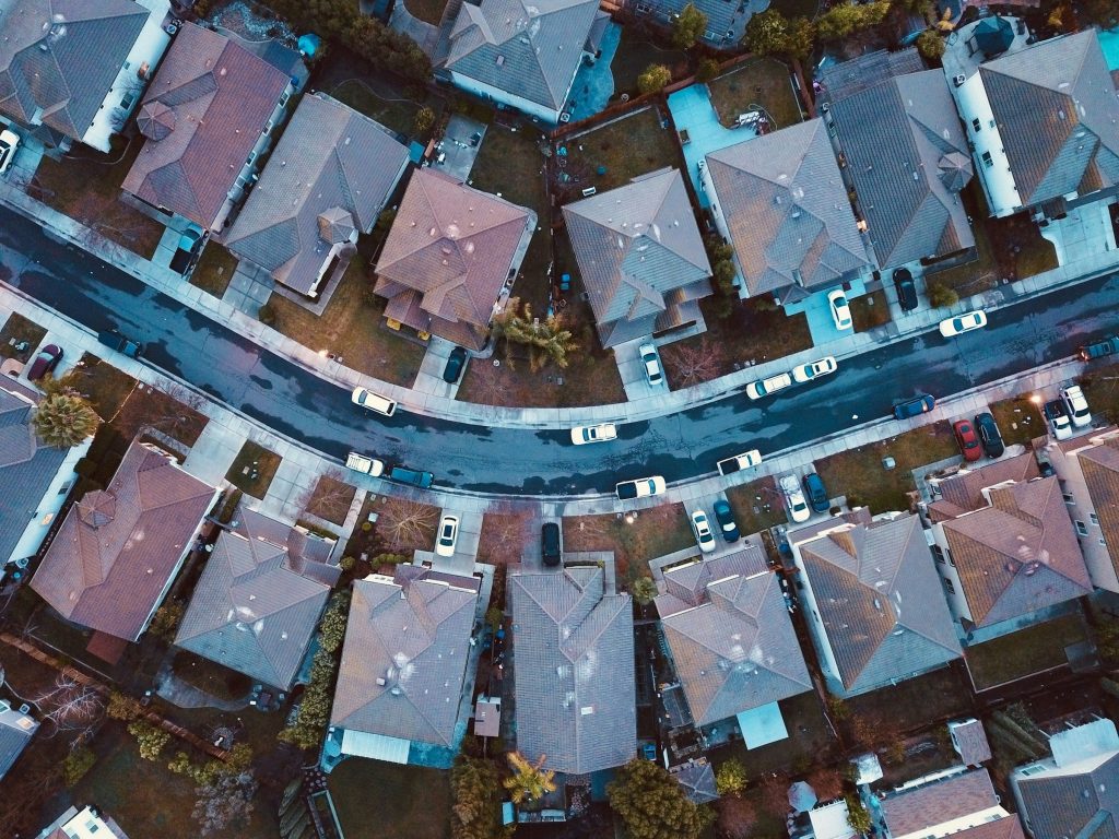 Tile-roofed houses and screened pools along a curving street, straight down