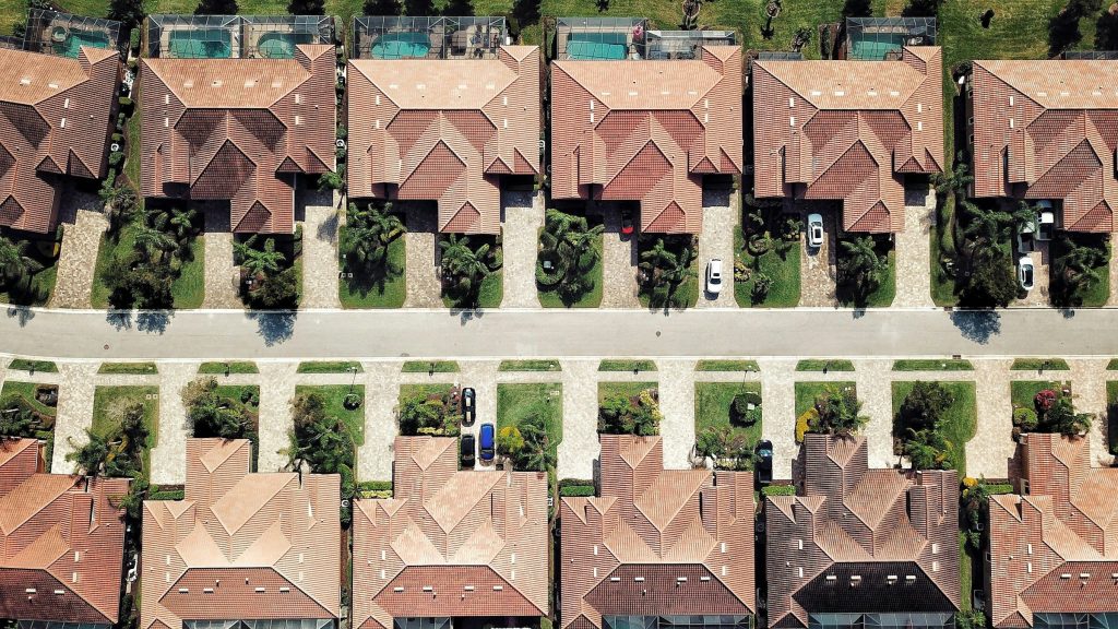 Rows of identical tile-roofed townhouses either side of a street, from above