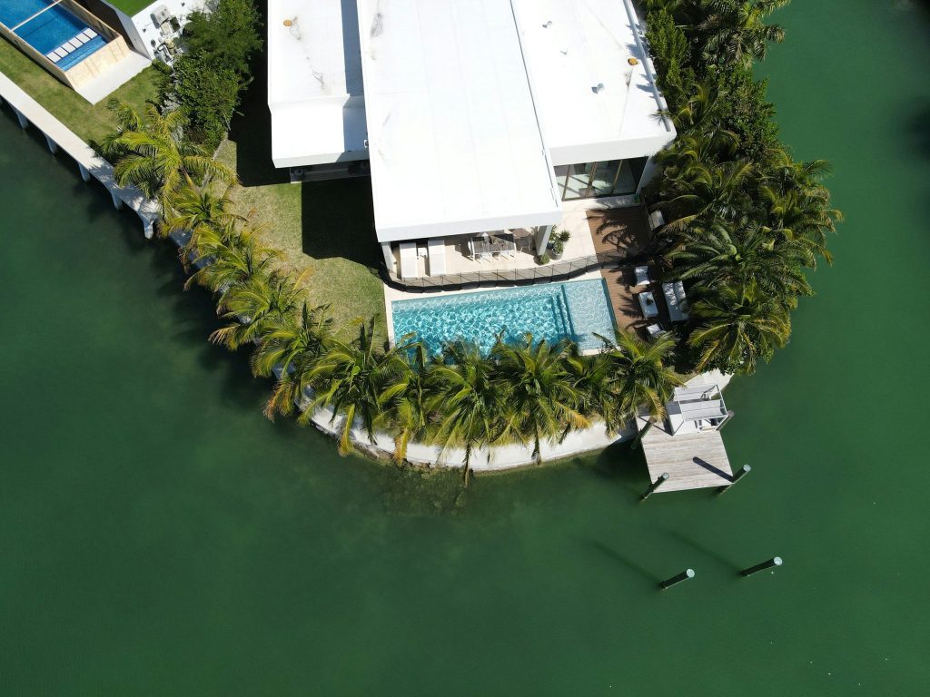 A waterfront house from above: pool, seawall and a dock on the point