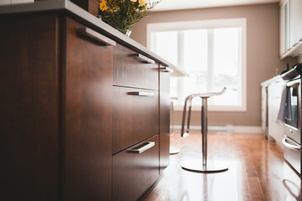 Dark wood drawers with long steel handles beside a bright window