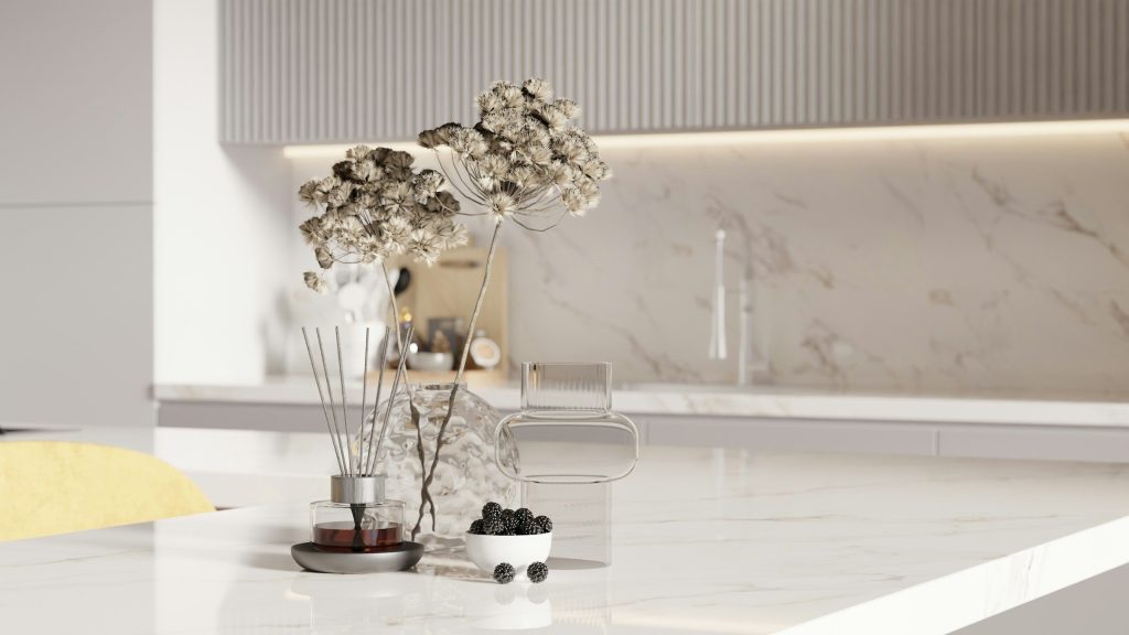 A marble counter and backsplash with dried flowers and a bowl of blackberries