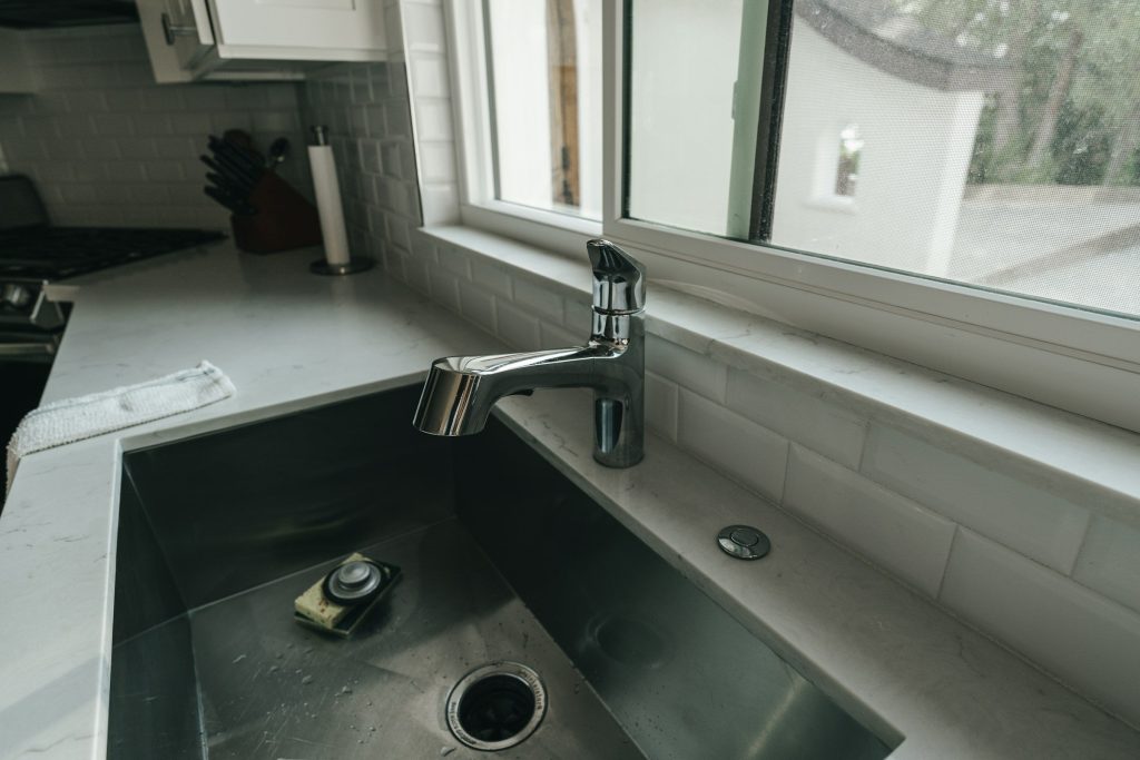 A deep stainless sink and a chrome tap under a kitchen window