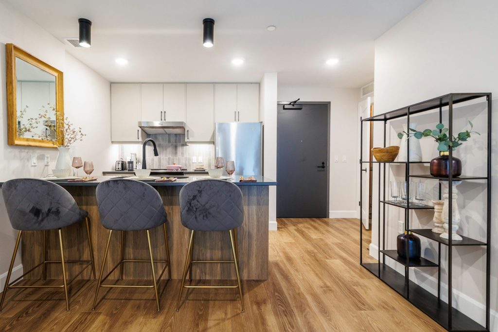 A breakfast bar with velvet stools between a kitchen and a hallway
