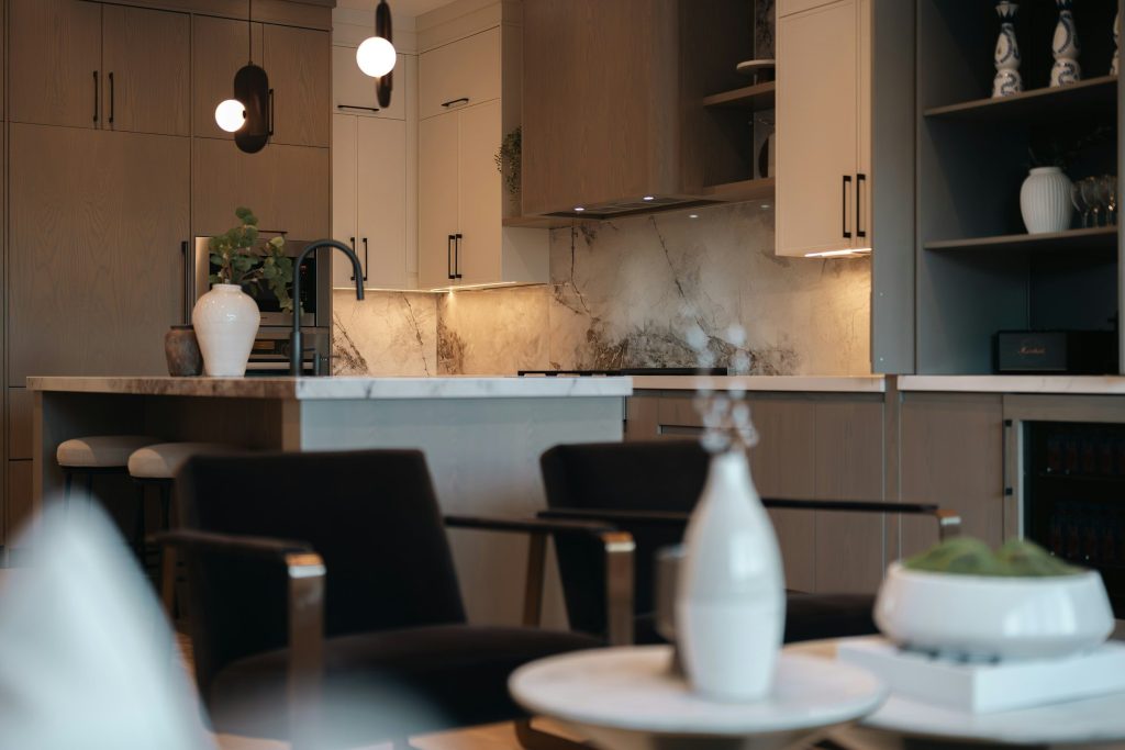 A warm kitchen of oak and stone seen past a dining table