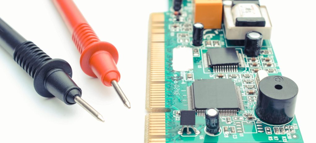 Two multimeter test probes resting against a green electronic control board, photographed close up