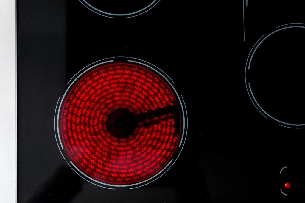 A radiant element glowing red on a black ceramic cooktop, the other zones unlit around it