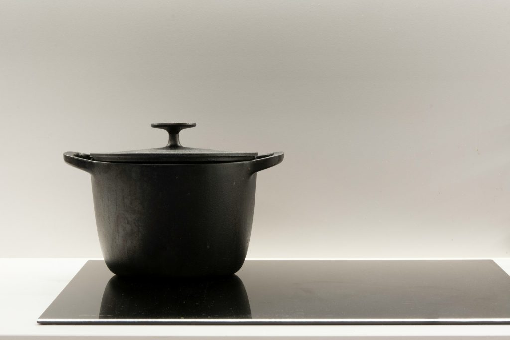 A black cast-iron casserole standing on an induction plate