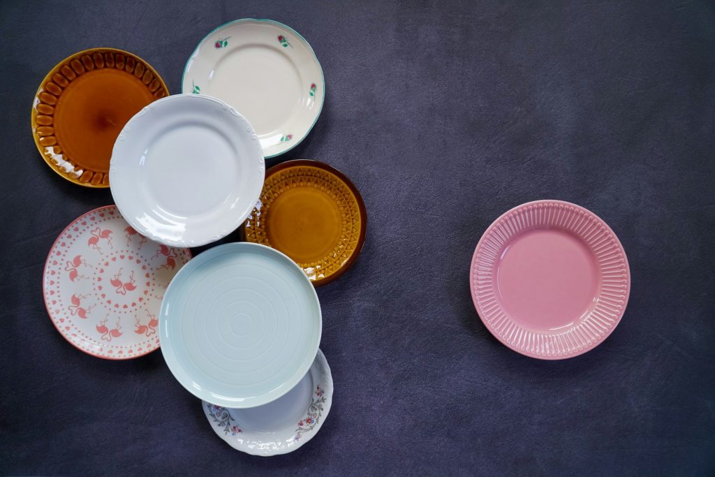 Seven plates of different patterns laid out on a slate surface