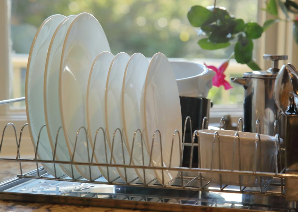 Plates and bowls draining in a rack by a bright window