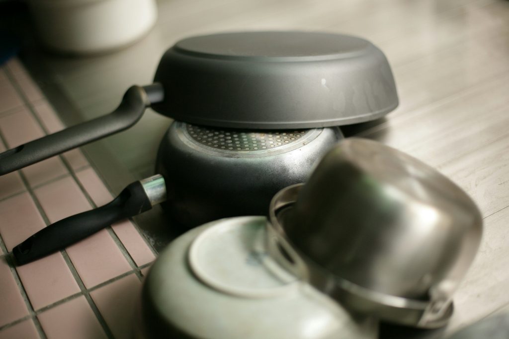 Pans and lids stacked upside down on a tiled counter