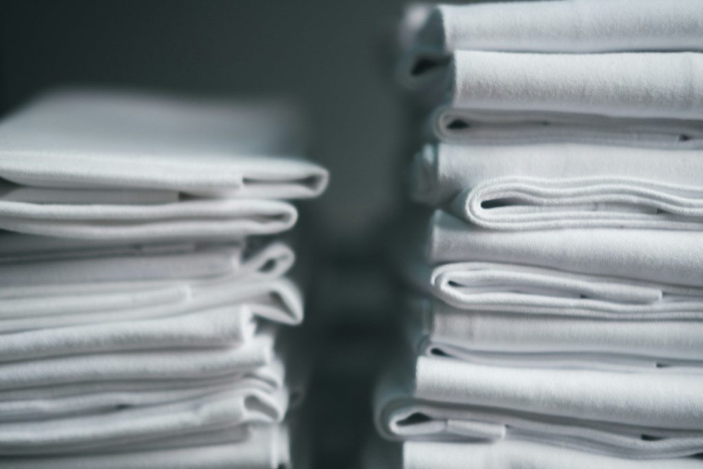 Two tall stacks of pressed white linen on a shelf