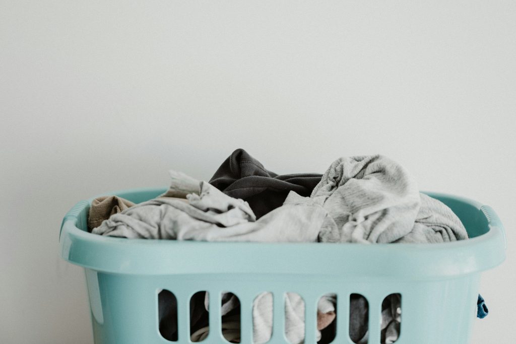 A pale laundry basket filled with clothes waiting to be washed